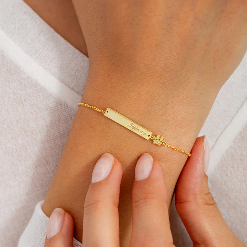 Bracelet fin en acier inoxydable doré avec plaque gravée et chaîne à maillons délicats.