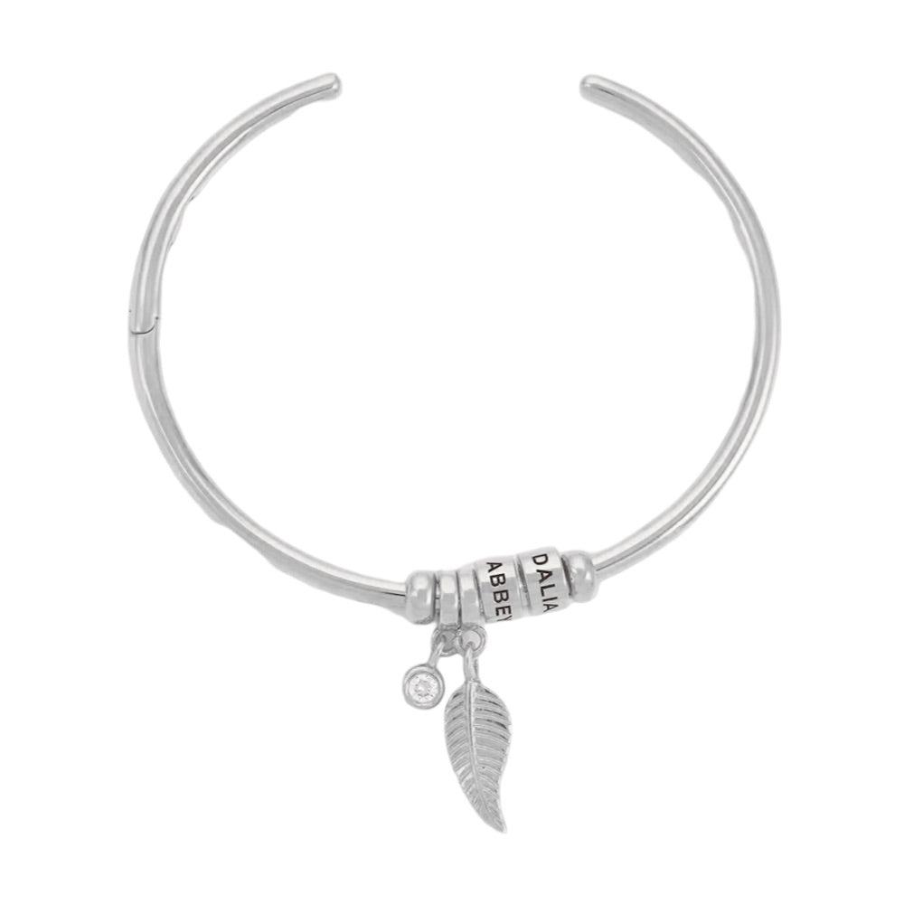 Bracelet ouvert argenté en acier inoxydable avec deux anneaux, breloques plume et strass.