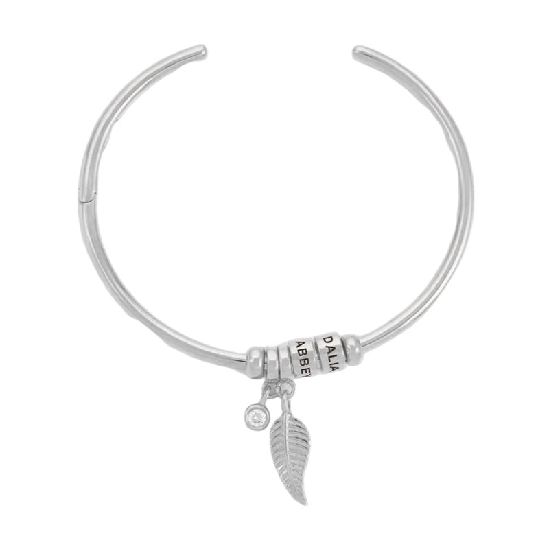 Bracelet ouvert argenté en acier inoxydable avec deux anneaux, breloques plume et strass.