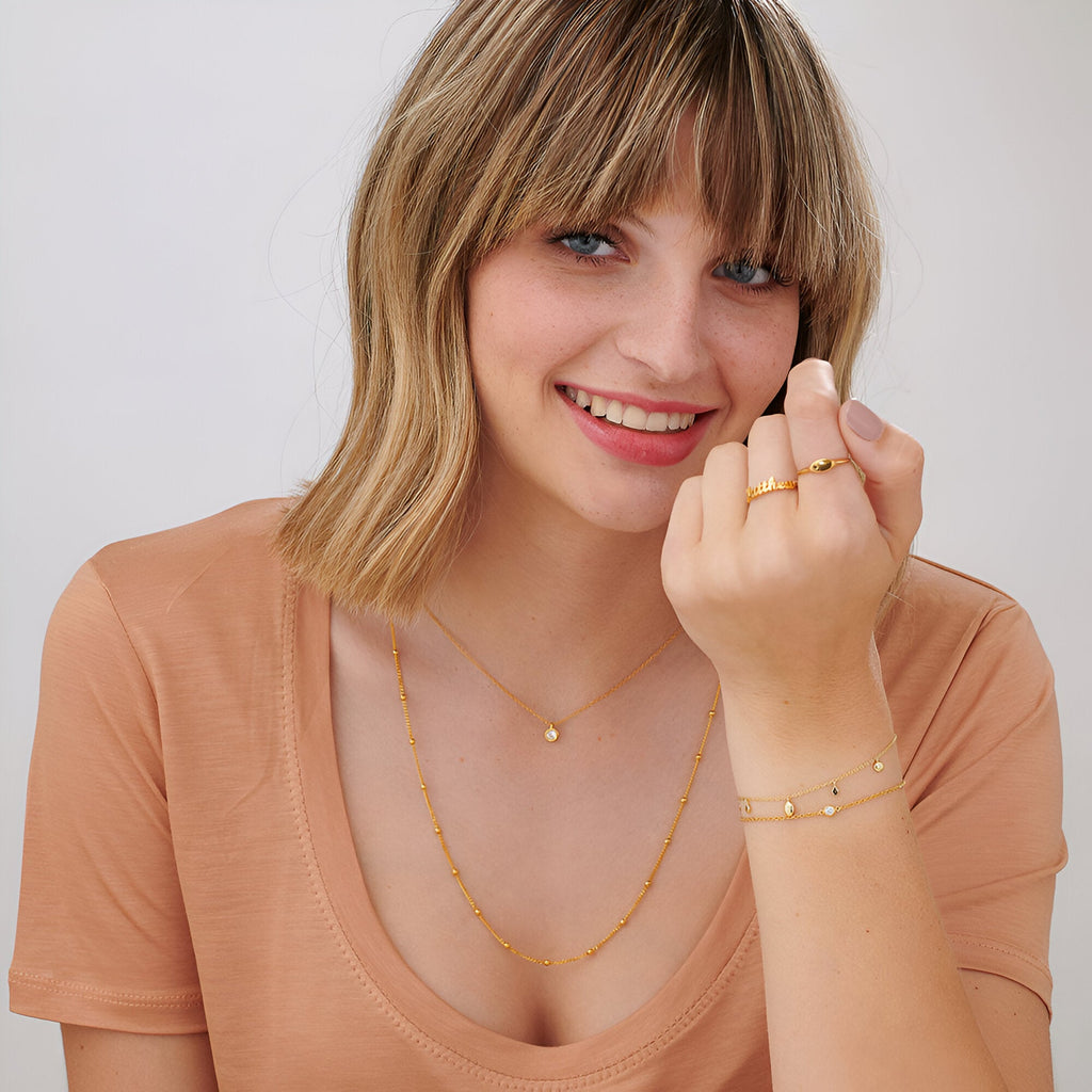 Bracelet fin en argent sterling avec petites perles rondes, porté avec collier et bagues assorties, style délicat et lumineux.