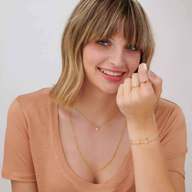 Bracelet fin en argent sterling avec petites perles rondes, porté avec collier et bagues assorties, style délicat et lumineux.