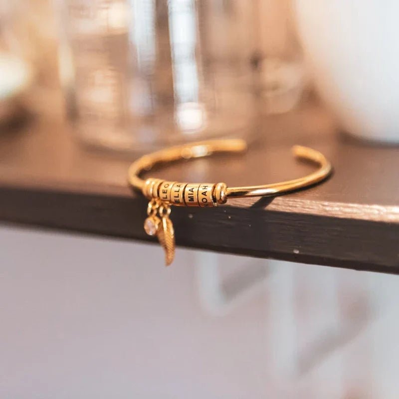 Bracelet doré en acier inoxydable à quatre anneaux avec breloque fine suspendue.