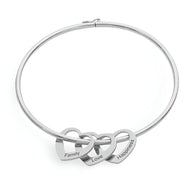 Bracelet rigide en titane argenté avec trois cœurs entrelacés gravés « Family », « Love », « Happiness ».