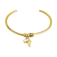 Bracelet jonc fin en acier inoxydable doré avec pendentifs plume et perle blanche.