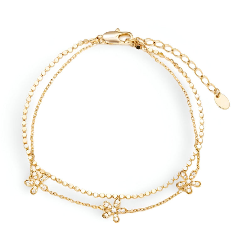 Bracelet double chaîne fine en or avec pendentifs pétales de fleur délicats.