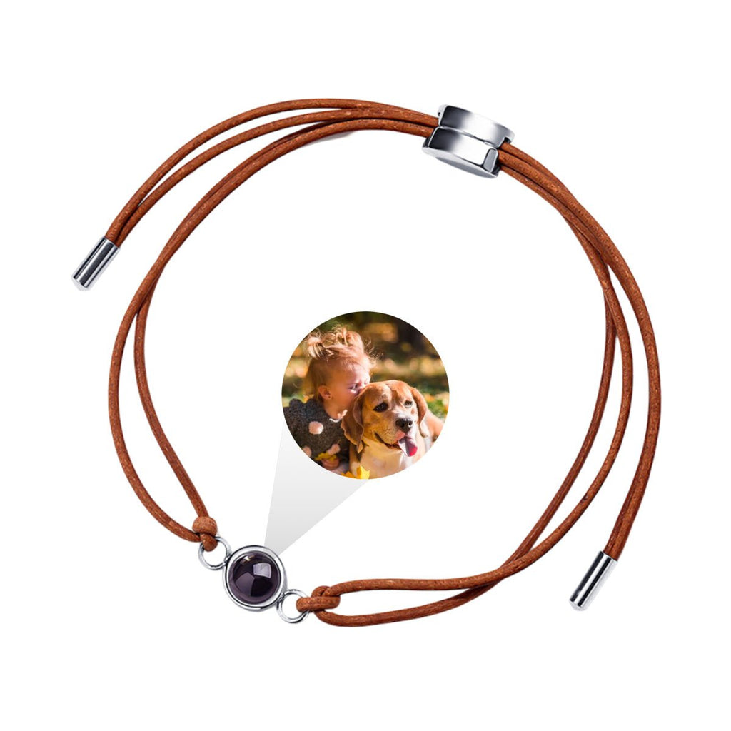 Bracelet en cuir marron à cordon réglable avec pendentif rond argenté contenant une photo cachée.