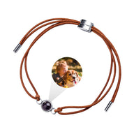 Bracelet en cuir marron à cordon réglable avec pendentif rond argenté contenant une photo cachée.
