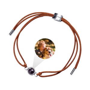 Bracelet en cuir marron à cordon réglable avec pendentif rond argenté contenant une photo cachée.