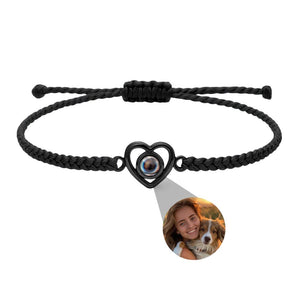 Bracelet noir tressé ajustable avec pendentif cœur en argent projetant une photo personnalisée ronde.