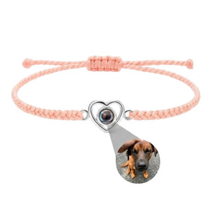 Bracelet rose en corde tressée avec pendentif cœur argenté projetant photo personnalisée d’un chien.