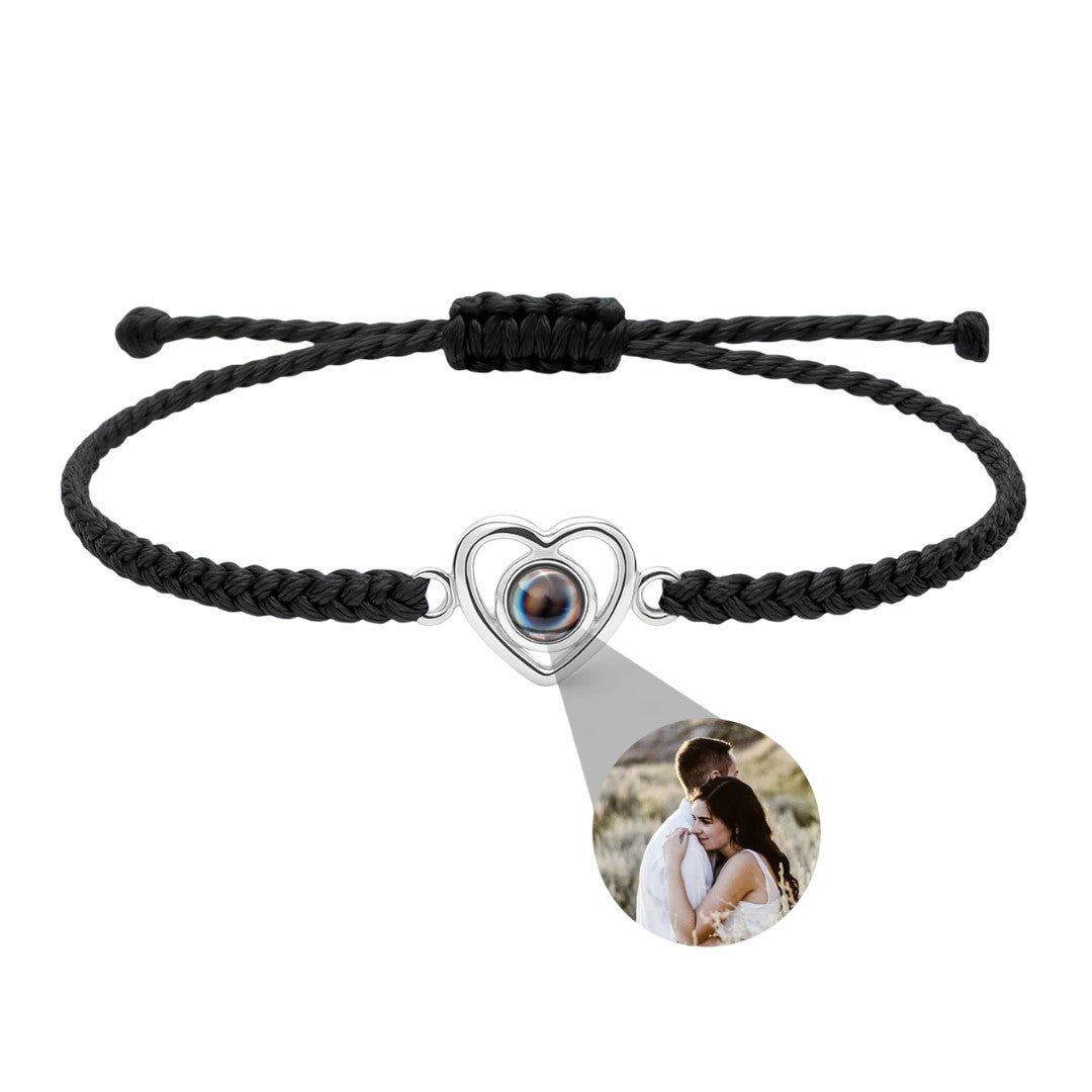 Bracelet noir tressé avec pendentif cœur en argent projetant une photo personnalisée.