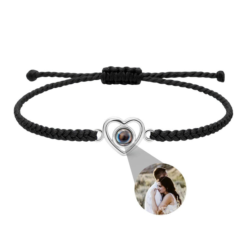 Bracelet noir tressé avec pendentif cœur en argent projetant une photo personnalisée.