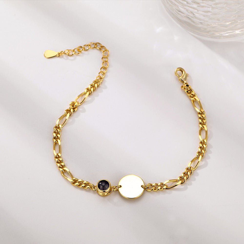 Bracelet doré maille figaro avec médaille ronde lisse et petite pierre noire sertie.