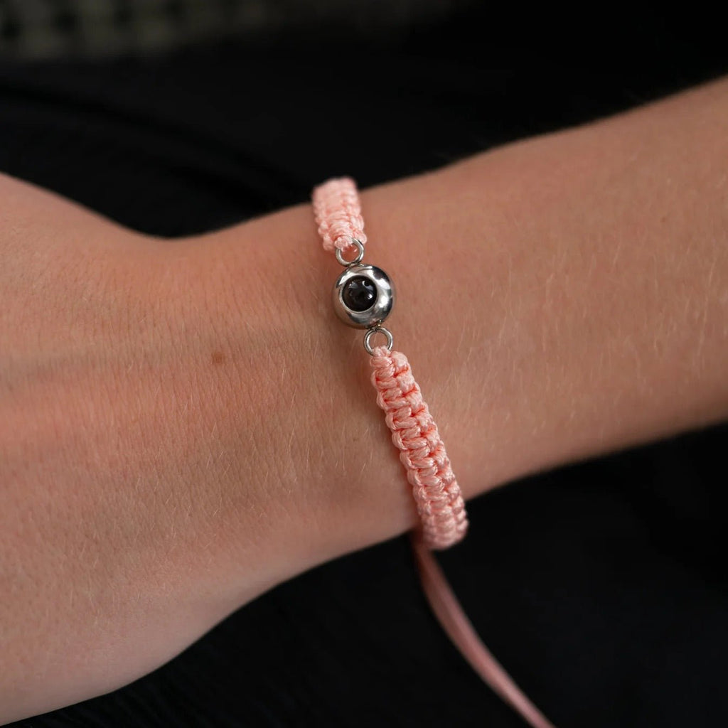 Bracelet rose en corde tressée avec breloque ronde en titane noir au centre.