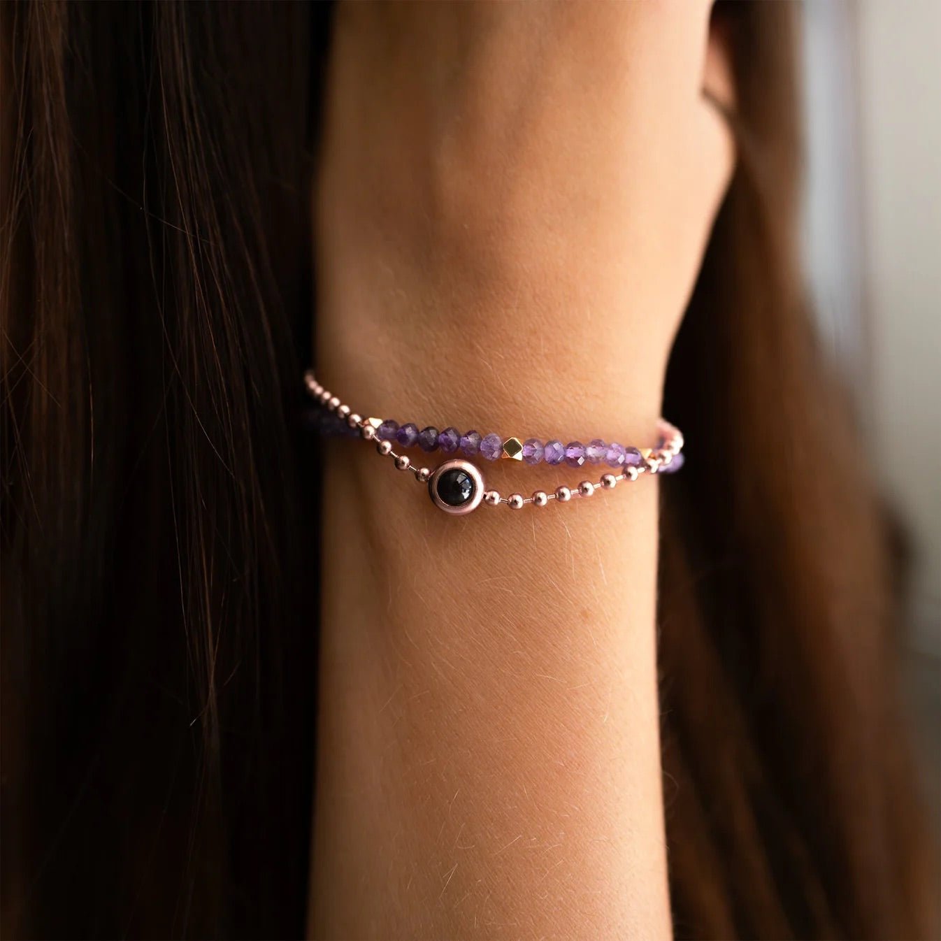 Bracelet double rang en pierres naturelles violettes avec pendentif photo rond argenté sur poignet féminin.