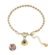 Bracelet femme en acier inoxydable doré à billes avec pendentif photo à nœud central et chaîne réglable.