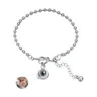 Bracelet en acier inoxydable argenté à maillons ronds avec nœud central et pendentif photo personnalisé.