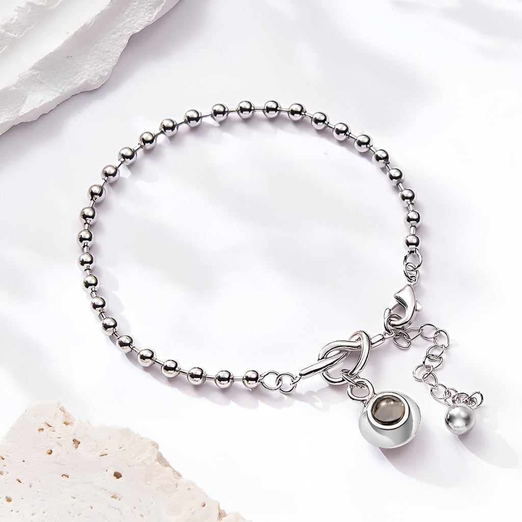 Bracelet en acier inoxydable argenté avec nœud central et pendentif photo rond personnalisable.