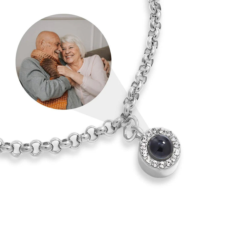 Bracelet en acier inoxydable argenté avec maillon rolo et pendentif rond serti d’un cercle de strass et d’une pierre noire.