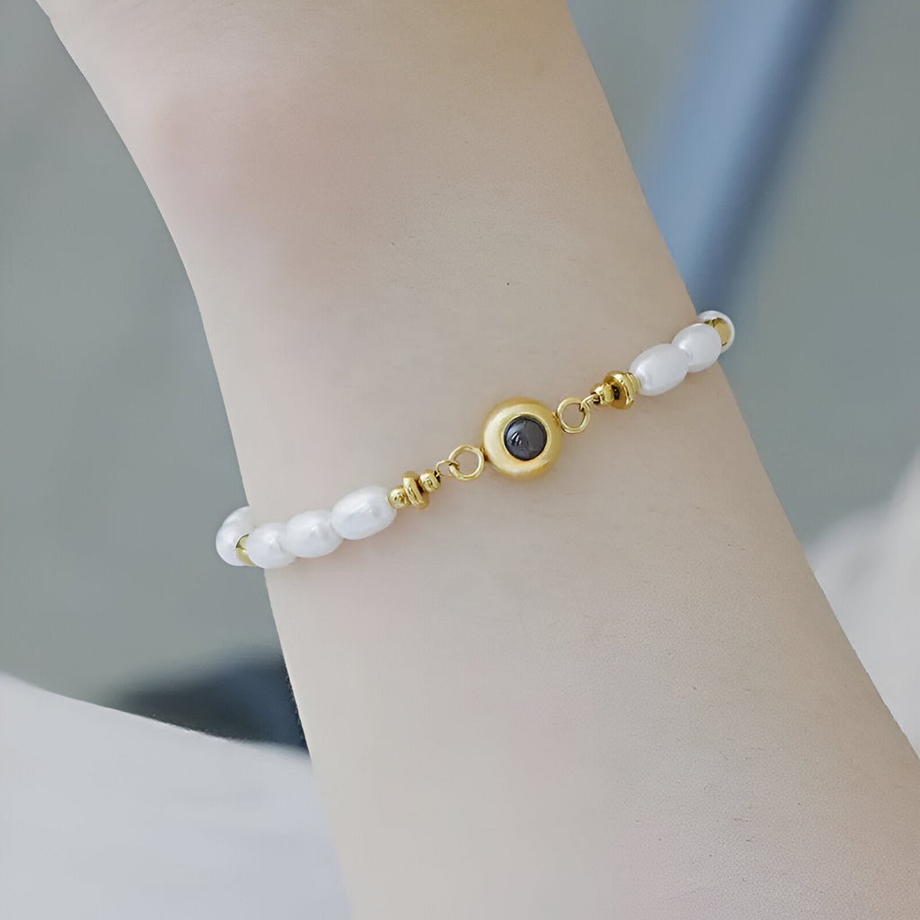 Bracelet fin en acier inoxydable doré avec perles d'eau douce blanches et médaille centrale personnalisable.