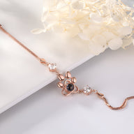 Bracelet en or rosé avec pendentif patte de chien et pierre centrale personnalisable.