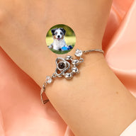 Bracelet en argent sterling avec pendentif patte de chien orné de pierres brillantes sur poignet féminin.