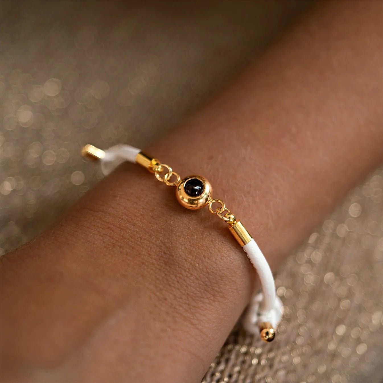 Bracelet en cuir blanc avec pendentif photo rond en acier inoxydable doré et détail noir, style élégant et moderne.