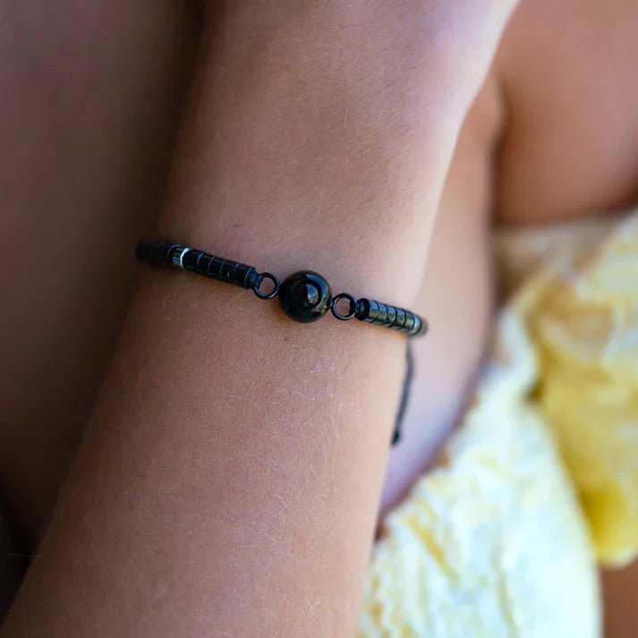 Bracelet ajustable en pierres heishi naturelles noires avec médaillon rond central lisse, style épuré et élégant.