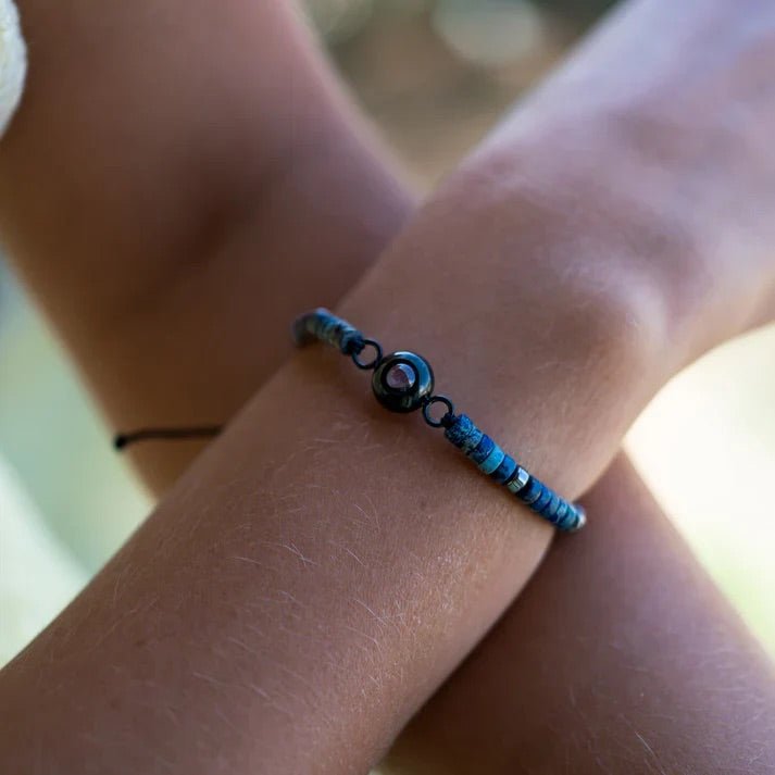 Bracelet heishi en pierres naturelles bleu turquoise avec médaillon photo rond noir sur poignet.