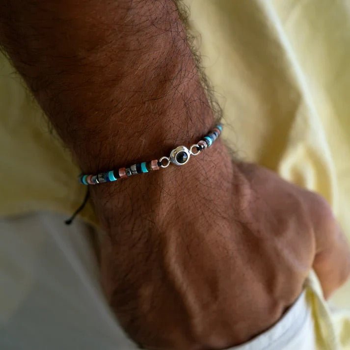 Bracelet pour homme en pierres heishi multicolores avec perle centrale œil grec noir et blanc, finition cordon ajustable.