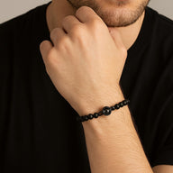 Bracelet perles noires d’onyx avec médaille photo personnalisée métallisée sur poignet masculin.