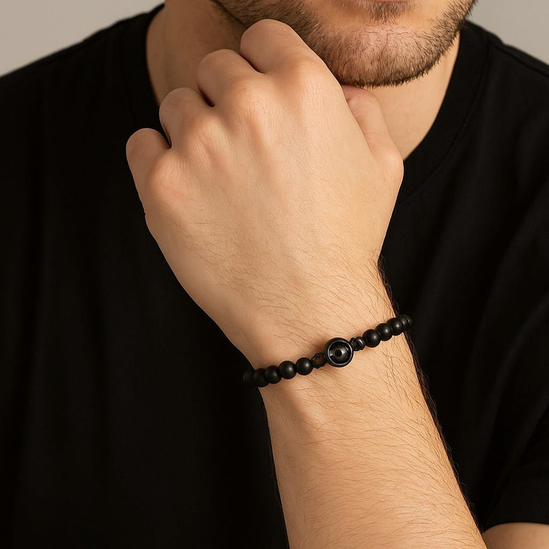 Bracelet perles noires d’onyx avec médaille photo personnalisée métallisée sur poignet masculin.