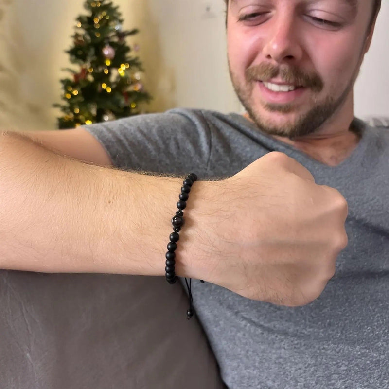 Bracelet en pierres naturelles noires rondes, style Amaru, portée ajustable sur poignet masculin.