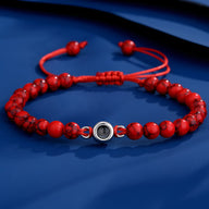 Bracelet rouge en pierres naturelles avec lien coulissant et détail photo central en métal argenté.