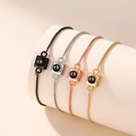 Bracelets photo personnalisés en titane avec charm carré, finitions noir, argent, or rosé et or brillant.