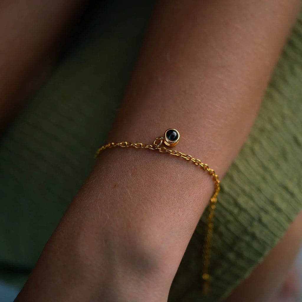 Bracelet fin en argent 925 doré avec petit médaillon rond noir, style délicat et minimaliste.
