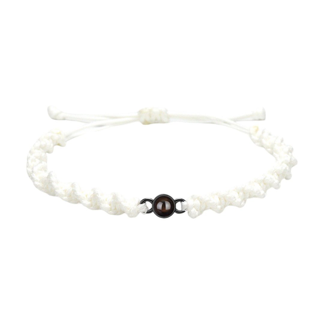 Bracelet tressé en nylon blanc avec fermoir coulissant noir et perle centrale marron.