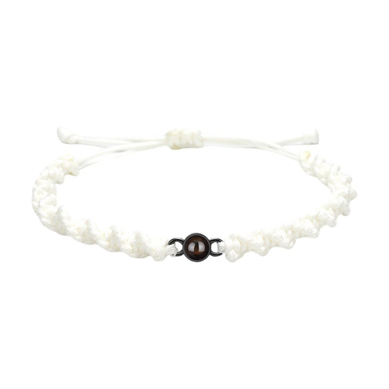 Bracelet tressé en nylon blanc avec fermoir coulissant noir et perle centrale marron.