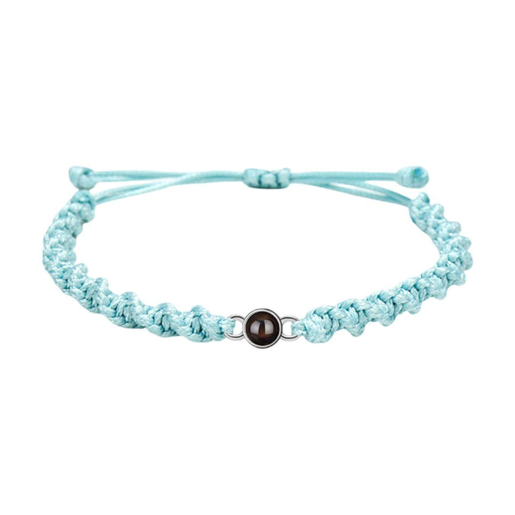 Bracelet tressé en nylon bleu clair avec fermoir coulissant métallique rond et photo projetée.