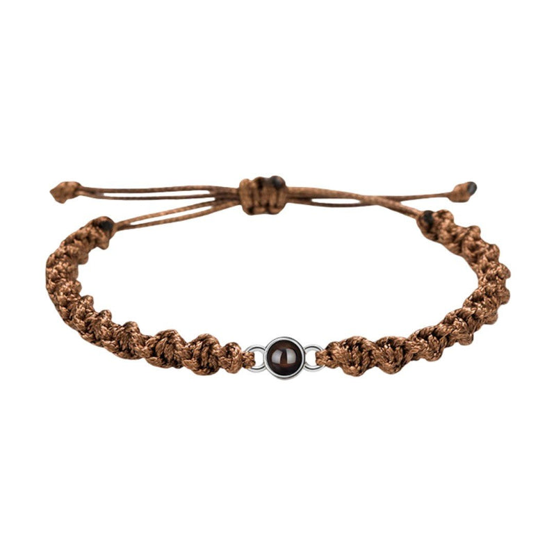 Bracelet tressé en nylon marron avec perle noire centrale et fermoir coulissant assorti.