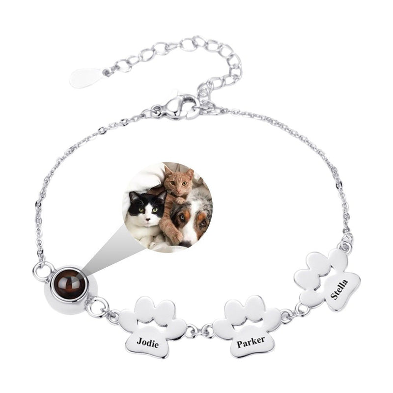 Bracelet fin en acier inoxydable argenté avec trois plaques à graver en forme de pattes et lentille photo intégrée.