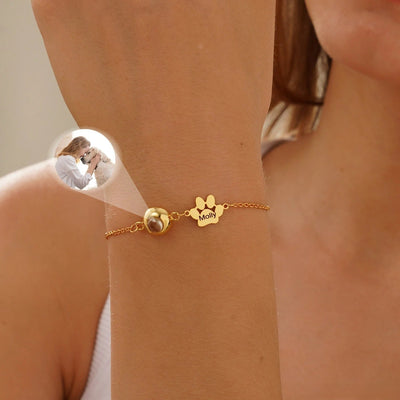 Bracelet or avec patte à graver en acier inoxydable et chaîne fine sur poignet féminin.