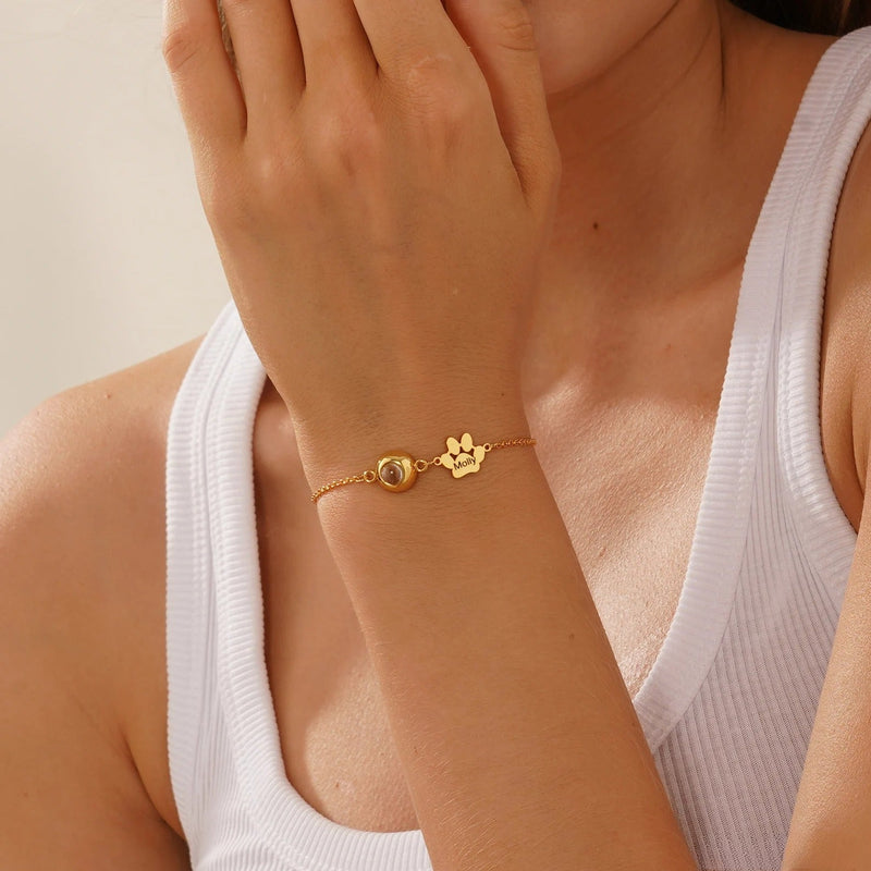 Bracelet fin en acier inoxydable or avec pendentif photo rond et patte à graver, fermé par chaîne ajustable.