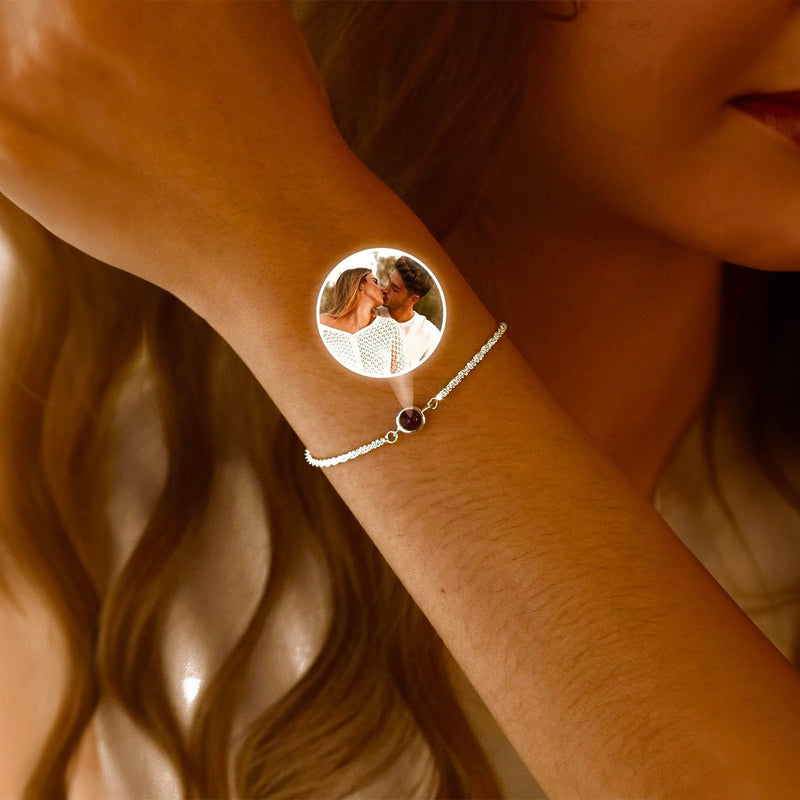 Bracelet en acier inoxydable argenté avec pendentif circulaire personnalisé affichant une photo projetée, porté au poignet.