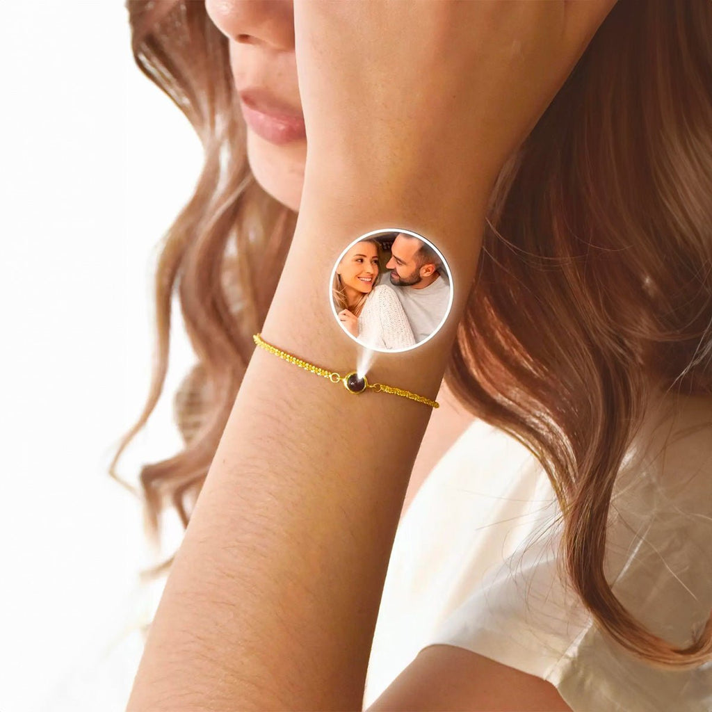 Bracelet fin en acier inoxydable finition or avec pendentif circulaire personnalisable photo, porté au poignet féminin.