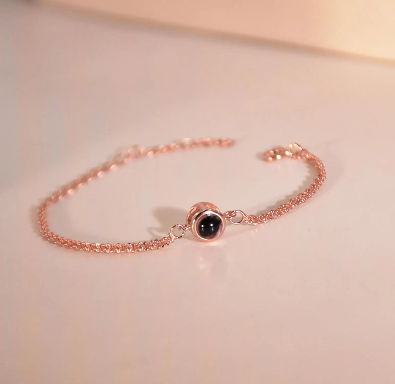 Bracelet fin en acier inoxydable plaqué or rose avec projection photo circulaire au centre.