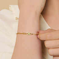 Bracelet fin en titane doré avec pierre de naissance verte, maillons ovales élégants.