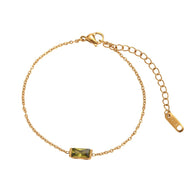 Bracelet fin en titane doré avec pierre rectangulaire verte et chaîne ajustable.