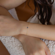 Bracelet fin en titane avec petite pierre bleue, style délicat et léger pour femme.