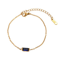 Bracelet fin en titane doré avec pierre rectangulaire bleu foncé, fermoir mousqueton.